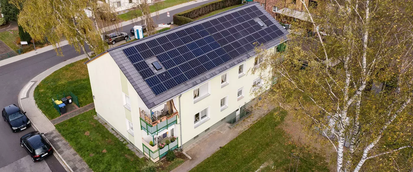 Mehrfamilienhaus von oben. Auf dem Dach befinden sich Photovoltaik-Anlagen
