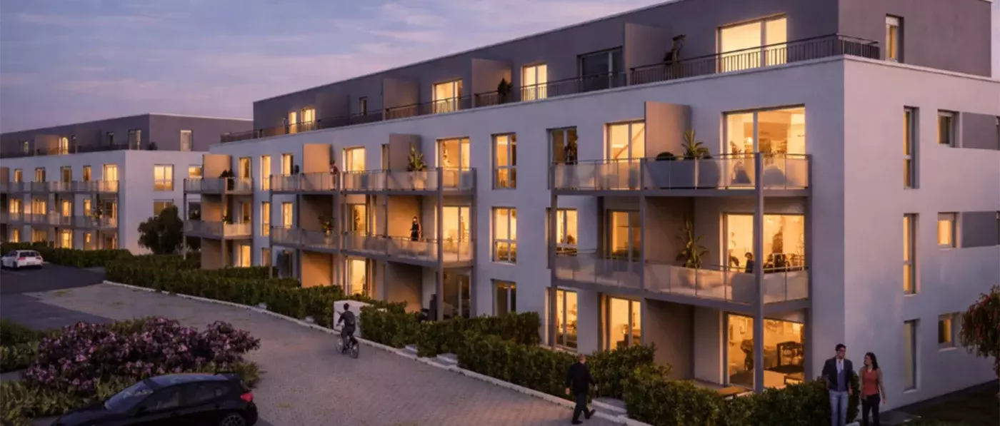 Ein Neubau in der Abenddämmerung. In den Wohnungen brennen Lichter. Vor dem Haus ist ein Stück Grünfläche mit Blumen zu erkennen
